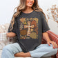 Model wearing a Comfort Colors® 1717 short sleeve t-shirt in dark charcoal gray (pepper) featuring a hand-drawn style Christian cross surrounded by brown, rust and muted green pumpkins with whimsical autumn flowers in mustard, orange, brown and gray.