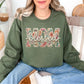 Model is wearing a Gildan 18000 sweatshirt in muted olive green (military green) featuring the word “mom” with “blessed” in script across it in a floral faux embroidery style design.
