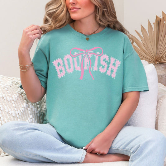 Model is wearing Navy blue (navy) Comfort Colors 17171 T-shirt featuring the word “BOOKISH” in a soft pink varsity type lettering with a pink bow accent centered above the text.