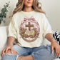 "Coquette Faux Embroidery Bible and Cross" graphic on soft off-white (ivory) T-Shirt. 