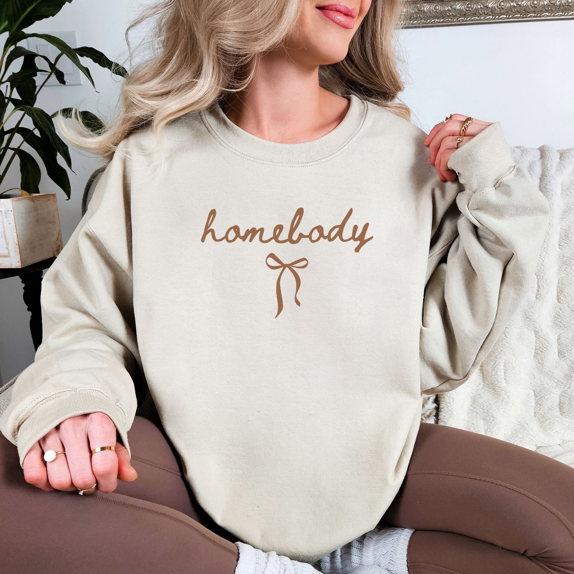 "Coquette Homebody" graphic on light warm beige (sand) sweatshirt.