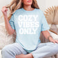 "Cozy vibes only" graphic on soft medium blue (chambray) T-shirt.