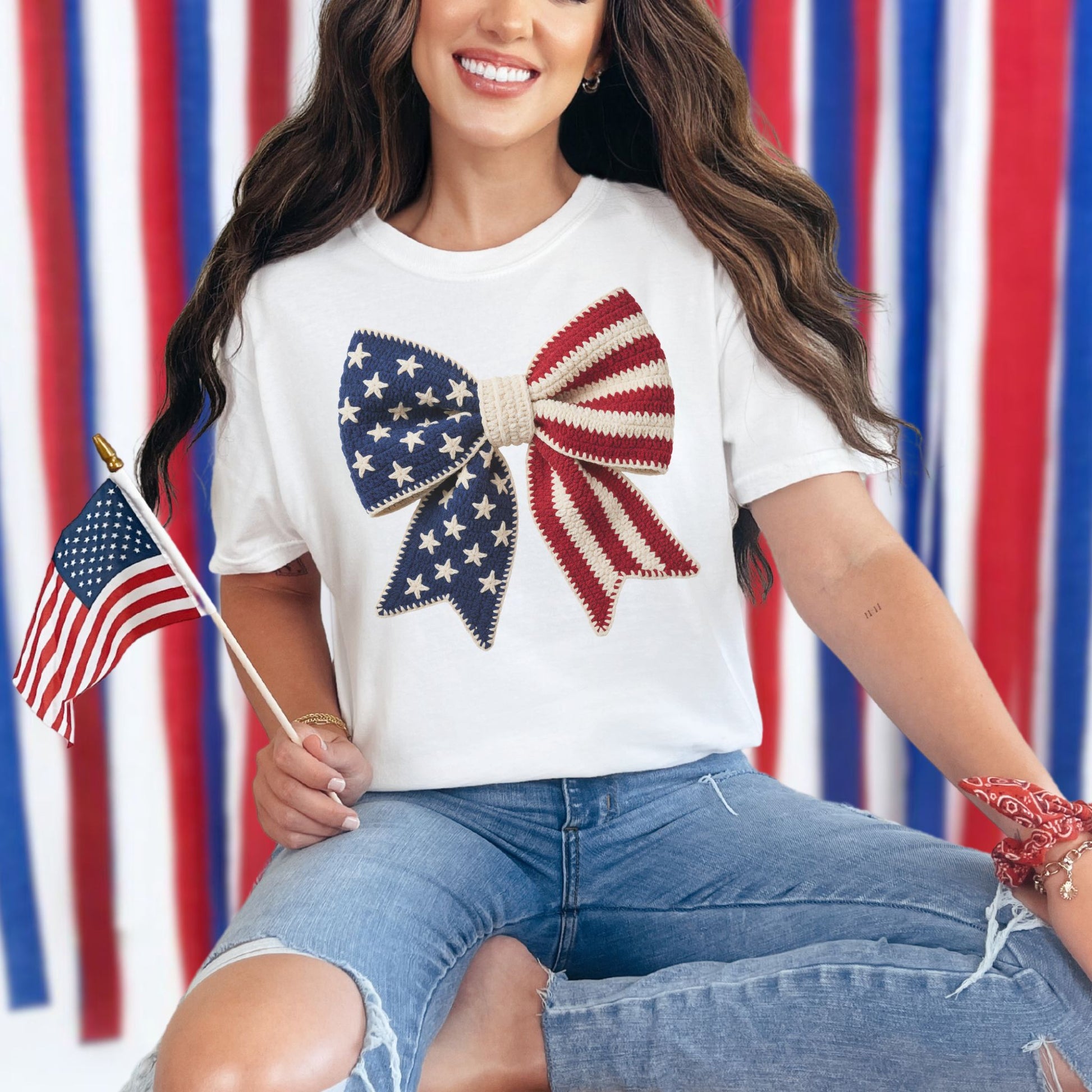 Model is wearing a Comfort Colors 1717 T-shirt in bright white (white) featuring a faux crochet American flag bow design with stars and stripes in a handmade-inspired style.