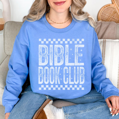 Model wearing a Gildan 18000 sweatshirt in soft sky blue (Carolina blue) featuring a distressed large word graphic that says, "Bible Book Club" Racer checkered stripes are on the top and bottom of the print.