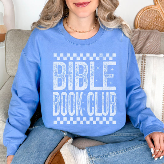 Model wearing a Gildan 18000 sweatshirt in soft sky blue (Carolina blue) featuring a distressed large word graphic that says, "Bible Book Club" Racer checkered stripes are on the top and bottom of the print.