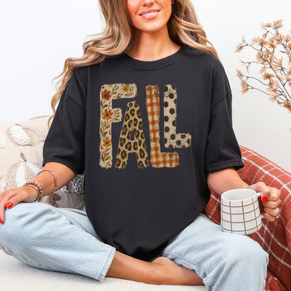 Model wearing a Comfort Colors® 1717 short sleeve t-shirt in black featuring large distressed “FALL” lettering filled with autumn floral, leopard print, orange gingham plaid, and brown polka dot patterns.