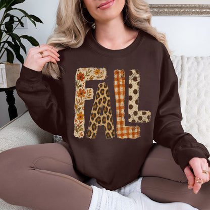 Model wearing a Gildan 18000 sweatshirt in deep brown (dark chocolate) featuring large distressed “FALL” lettering filled with autumn floral, leopard print, orange gingham plaid, and brown polka dot patterns.