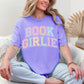 Model wearing a Comfort Colors 1717 t-shirt in a soft muted violet purple (violet) color featuring distressed pastel  colors of the words "Book Girlie" in a varsity letter font.