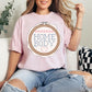 “Embroidery Hoop Home Body" graphic on soft pink (blossom) t-shirt.”
