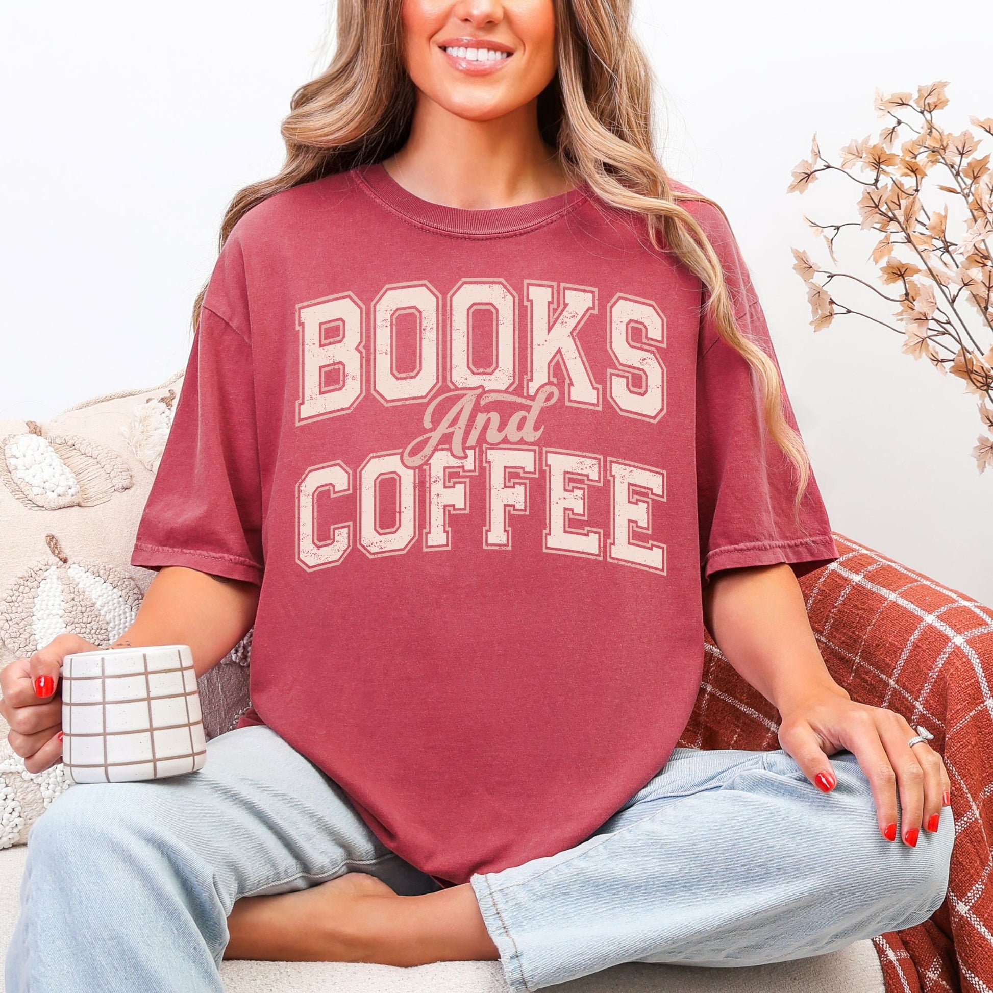 "Distressed Fall Books and Coffee" graphic in a cream color on muted warm brick red (brick) t-shirt.