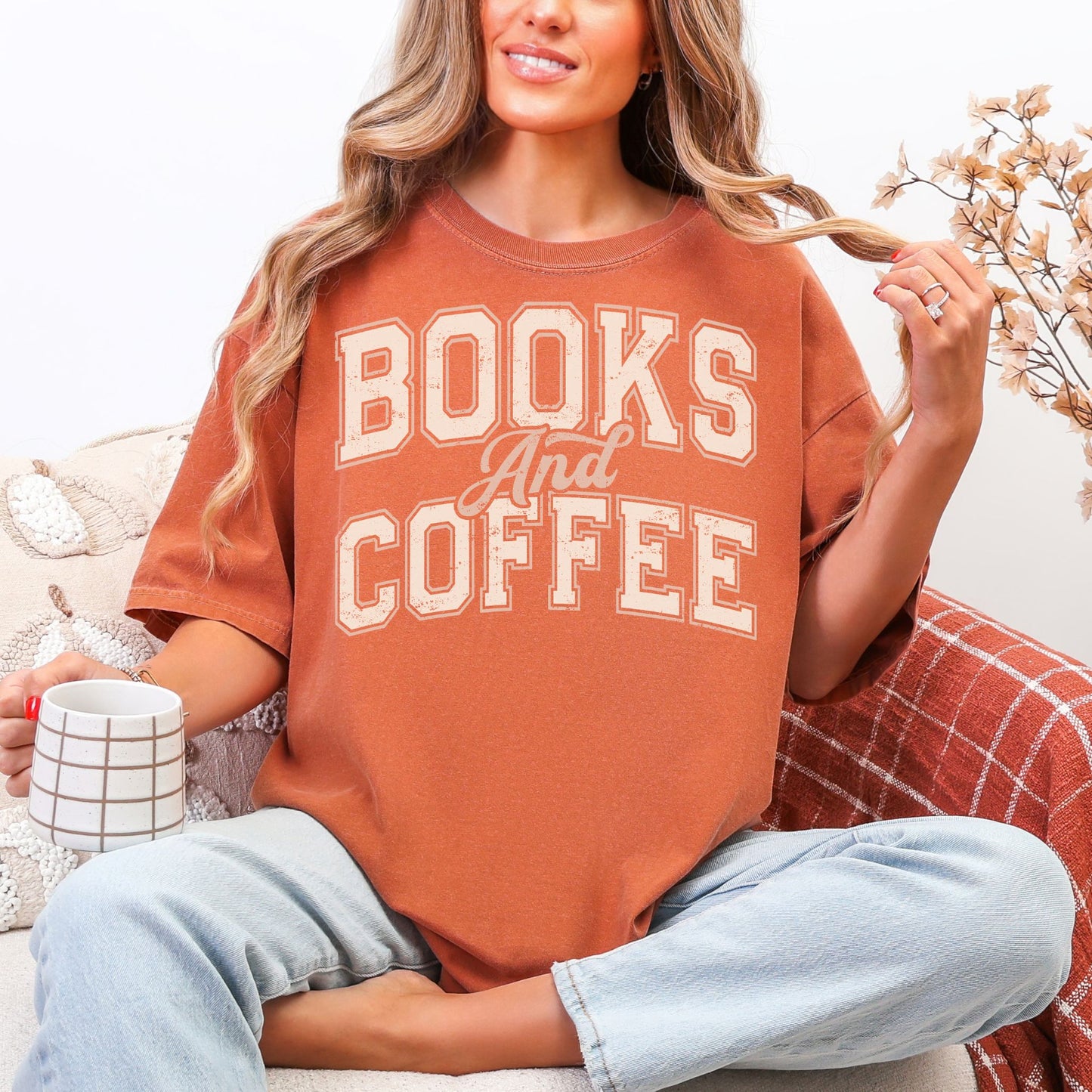 "Distressed Fall Books and Coffee" graphic in a cream color on muted burnt orange (yam) t-shirt.
