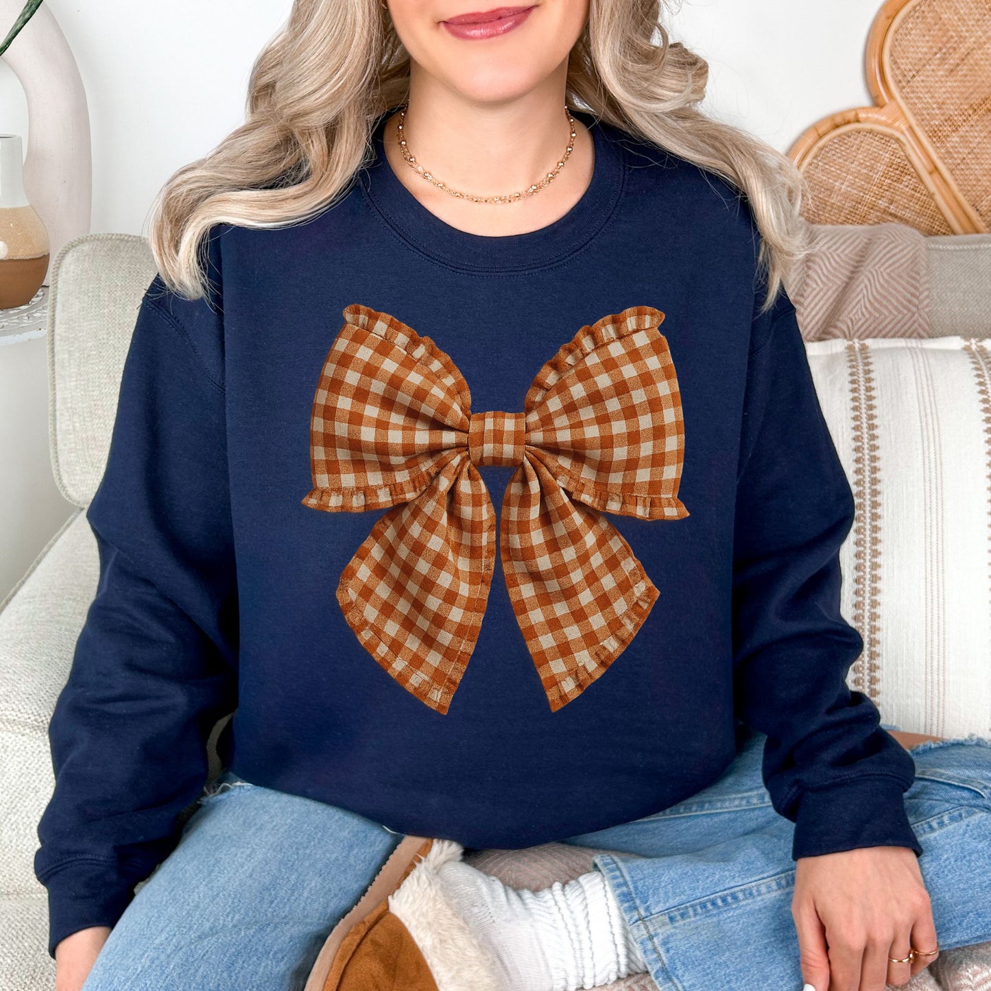 Model wearing a Gildan 18000 sweatshirt in dark blue (navy) featuring a large brown-and-cream gingham bow with a fabric-inspired textured appearance.