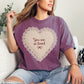 Model wearing a Comfort Colors 1717 deep berry pink (berry) t-shirt featuring a lace-style heart design with the words “You are so loved” and a small bow in the center. The design resembles embroidery stitching but is a printed illustration. Shown on a deep red (chili) Comfort Colors shirt.