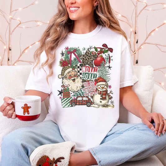 Model wearing a Comfort colors 1717 T-Shirt in white (White) featuring a distressed Christmas collage with Santa, a snowman, a red car, wrapped gifts, Christmas trees, ornaments, stars, greenery, leopard-print accents, and the words “Holly Jolly” and “It’s the most wonderful time of the year!”