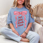 “Model wearing a Comfort Colors 1717 t-shirt in muted denim blue (washed denim) color featuring a graphic design of a large pink bow with the phrase "hot girl book club" underneath in between the ribbons.