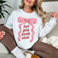 “Model wearing a Gildan 18000 sweatshirt in bright white (white) color featuring a graphic design of a large pink bow with the phrase "hot girl book club" underneath in between the ribbons.