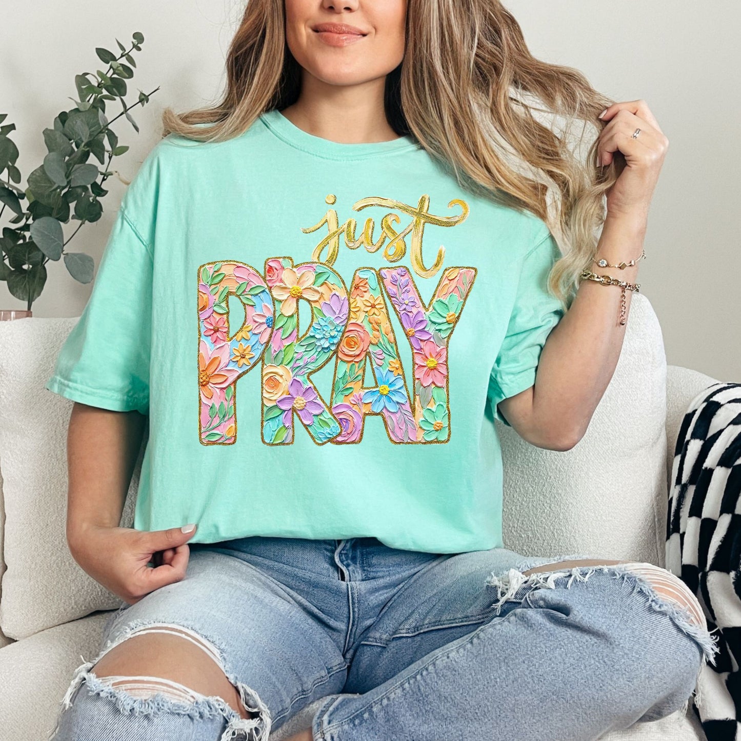 Model wearing a Comfort Colors 1717 soft aqua blue (island reef) T-shirt featuring a floral “Just Pray” Christian graphic with pastel flowers inside bold lettering and gold script text above, designed in a faux painted style.