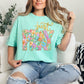 Model wearing a Comfort Colors 1717 soft aqua blue (island reef) T-shirt featuring a floral “Just Pray” Christian graphic with pastel flowers inside bold lettering and gold script text above, designed in a faux painted style.
