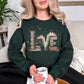 Model wearing a Gildan 18000 sweatshirt in deep forest green (forest green) featuring a whimsical stacked book graphic that spell the word ‘Love’. Along with tiny heart and branch accents.