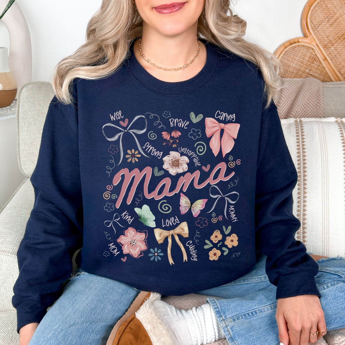 Model is wearing a Gildan 18000 t-shirt in deep navy blue (navy) featuring the word “mama” surrounded by bows, flowers, and doodle-style accents with words like strong, brave, caring, and loved in a soft feminine design.