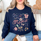 Model is wearing a Gildan 18000 t-shirt in deep navy blue (navy) featuring the word “mama” surrounded by bows, flowers, and doodle-style accents with words like strong, brave, caring, and loved in a soft feminine design.