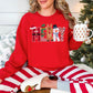 Model wearing a Gildan 18000 long-sleeve sweatshirt in true red (red) featuring the word “MERRY” in multicolored Christmas letters with faux felt and stitching details, including Santa, an elf, a reindeer, a snowman, and Christmas lights.