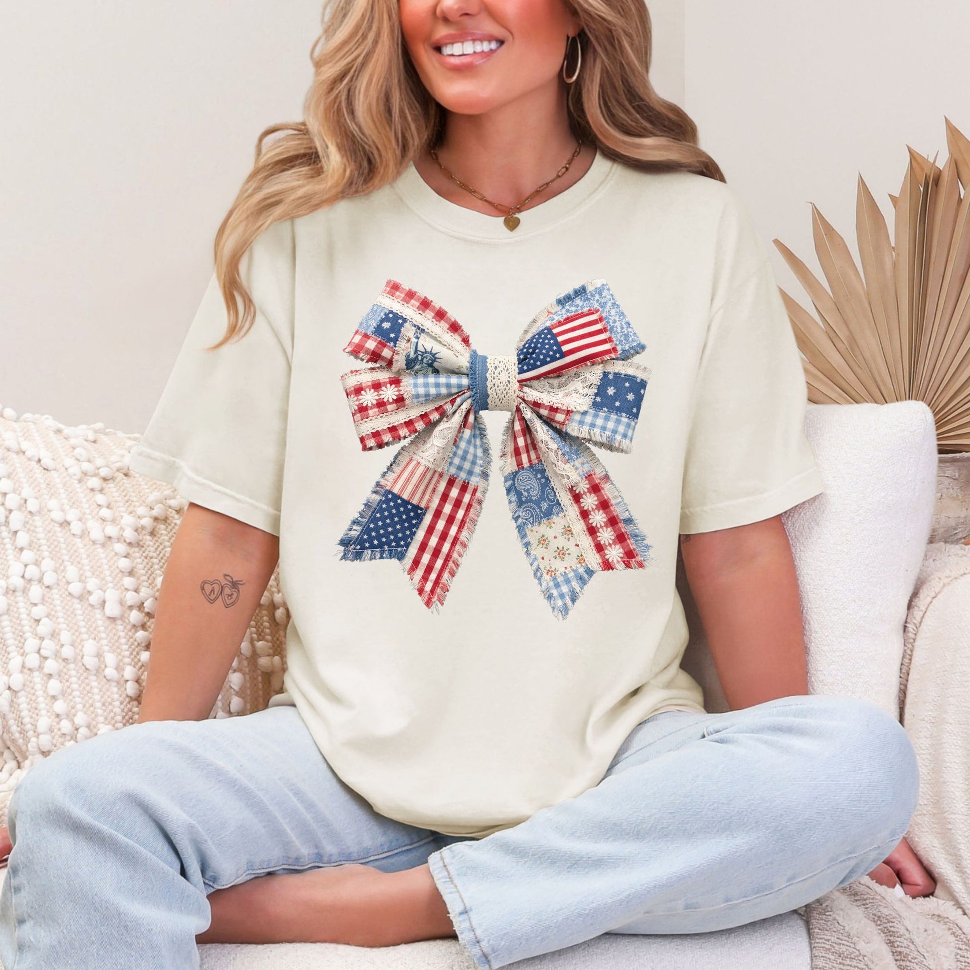 “Patriotic Patchwork Faux Bow" graphic on soft off-white (ivory) t-shirt.