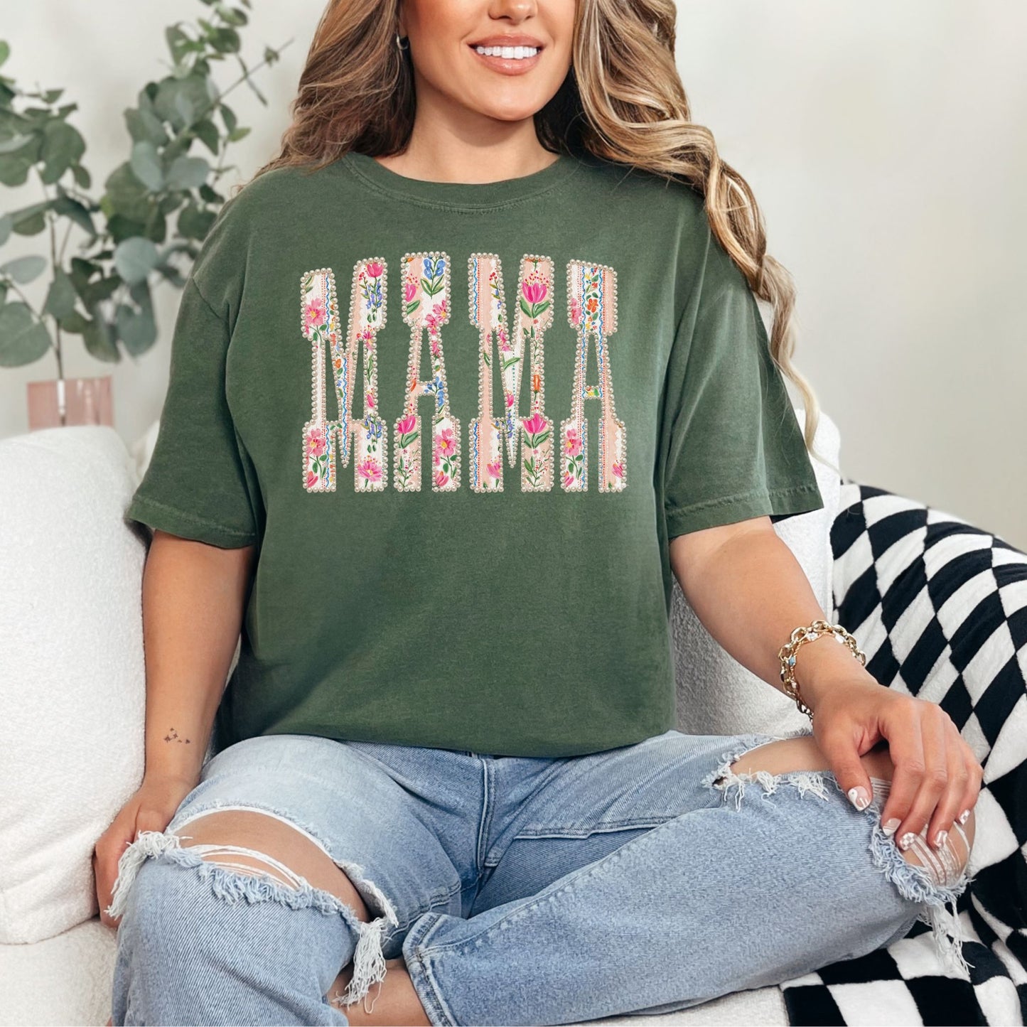 Model is wearing a Comfort Colors 1717 t-shirt in light earthy beige (hemp) featuring the word “mama” in floral-patterned letters with pearl-style detailing in a soft feminine design.
