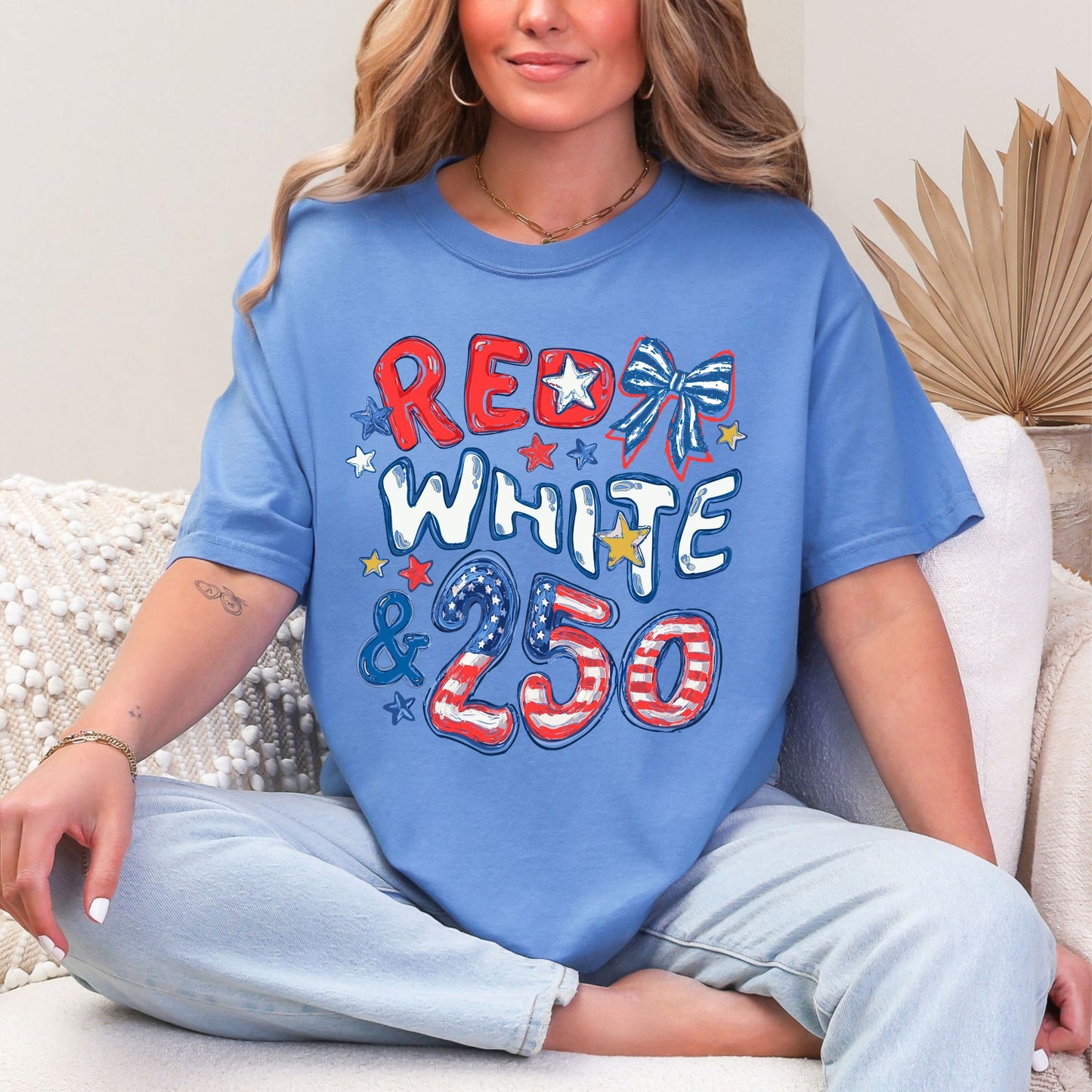 Model is wearing a Comfort Colors 1717  t-shirt in muted blue-green (mystic blue) featuring the phrase “Red White & 250” in patriotic doodle-style lettering with stars and a striped bow in red, white, and blue.