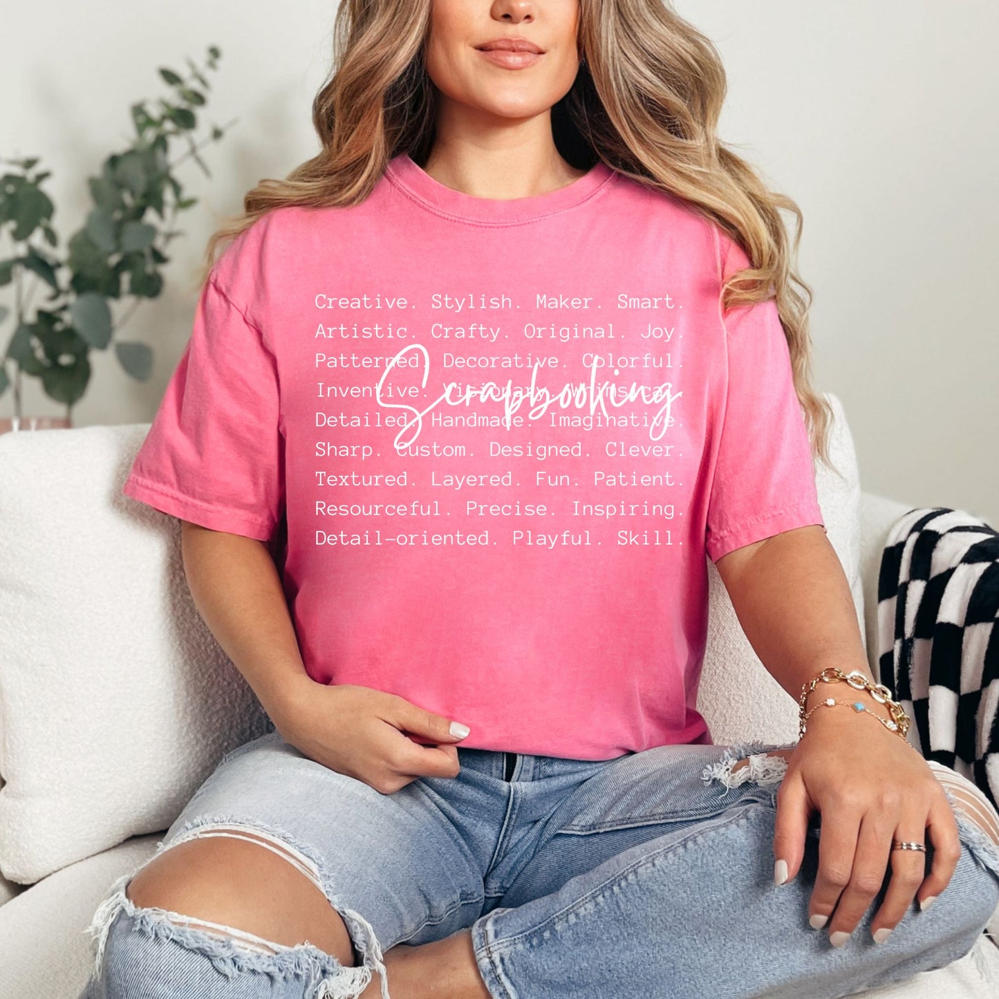 Model wearing a Comfort Colors 1717 t-shirt in a bright raspberry pink (crunchberry) color featuring a graphic design listing words that describe scrapbooking like "patient", "original", "joy" and "detailed". Over top of the words is the word "Scrapbooking" in bold cursive.