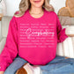 Model wearing a Gildan 18000 Sweatshirt in a bright pink (heliconia) color featuring a graphic design listing words that describe scrapbooking like "patient", "original", "joy" and "detailed". Over top of the words is the word "Scrapbooking" in bold cursive.