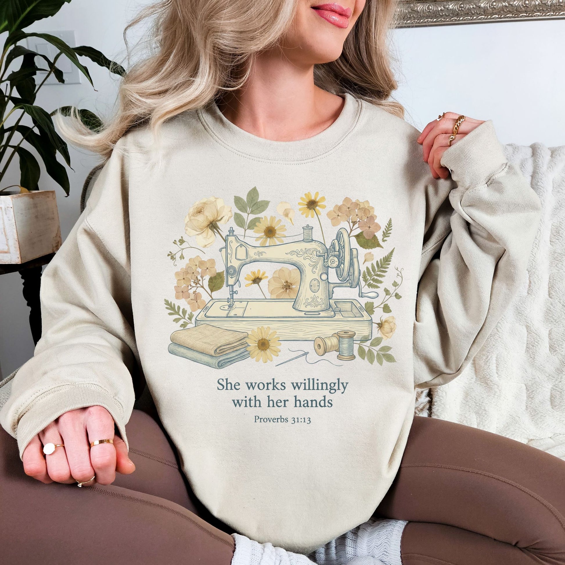 "Sewing she works willingly" graphic on light warm beige (sand) sweatshirt.
