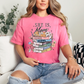 "She is Mom" graphic on bright raspberry pink (crunchberry) T-Shirt.