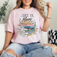 "She is Mom" graphic on soft pink (blossom) T-Shirt.