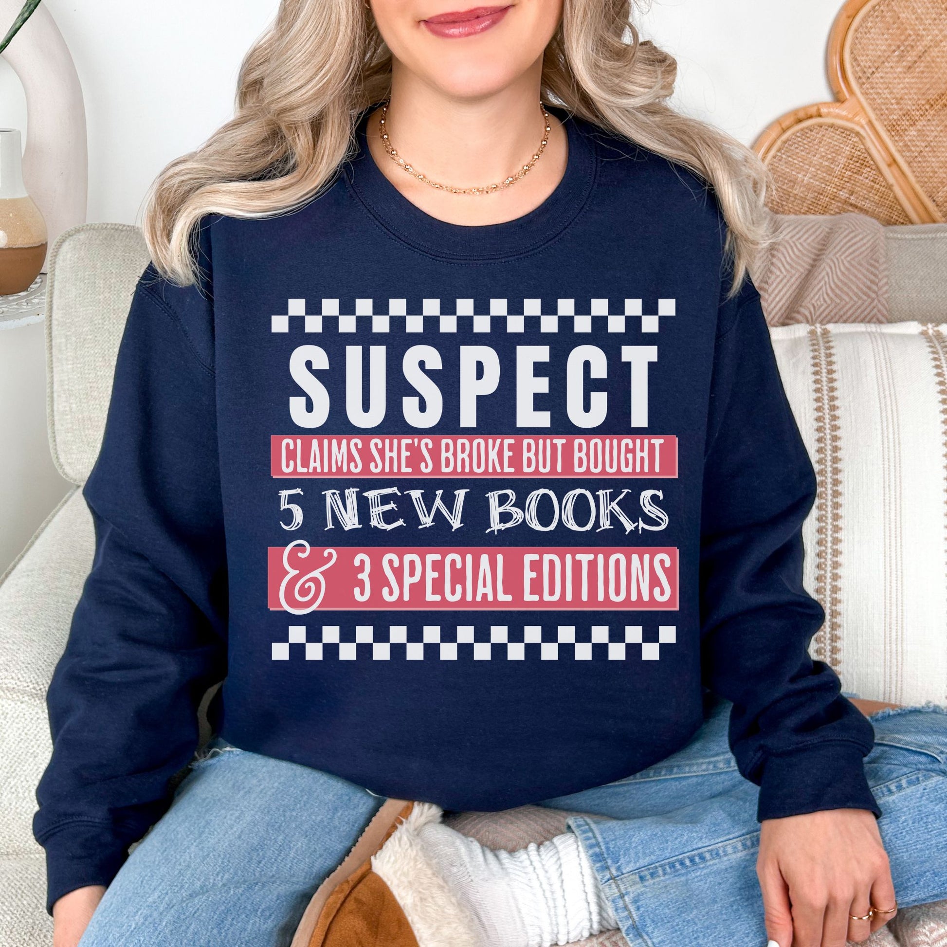Model wearing a deep navy blue (navy) Gildan 18000 Sweatshirt featuring wording that says "Suspect claims she's tired but stays up reading until 2 am" printed graphic with checkered strips on the top and bottom of the graphic.