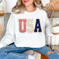 Model wearing a Gildan 18000 sweatshirt in very white (white) with a patriotic “USA” design featuring striped, knit-style, and star patterns accented with lace-style borders in a faux embroidery style.