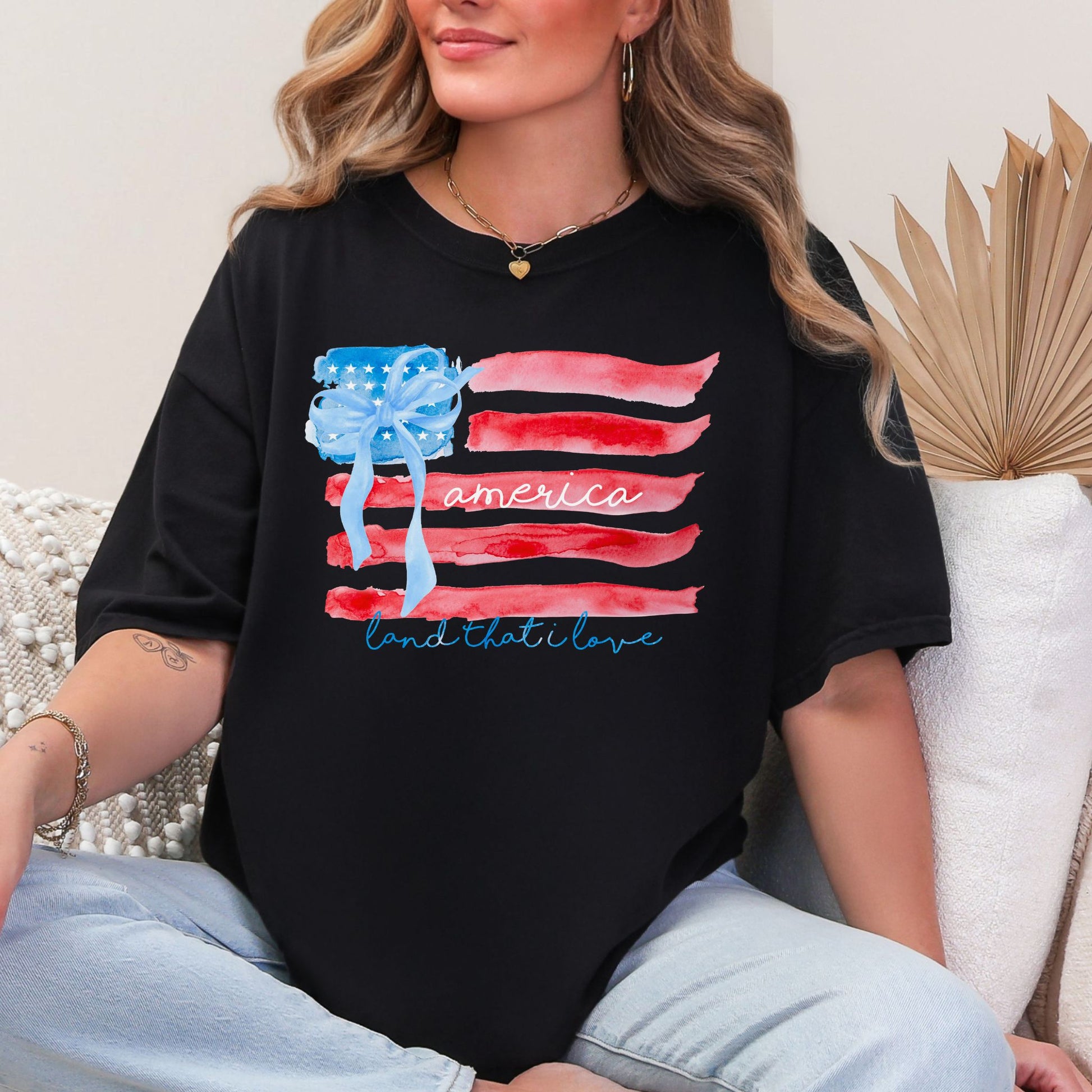 "Coquette Watercolor American Flag" graphic on a black T-shirt.