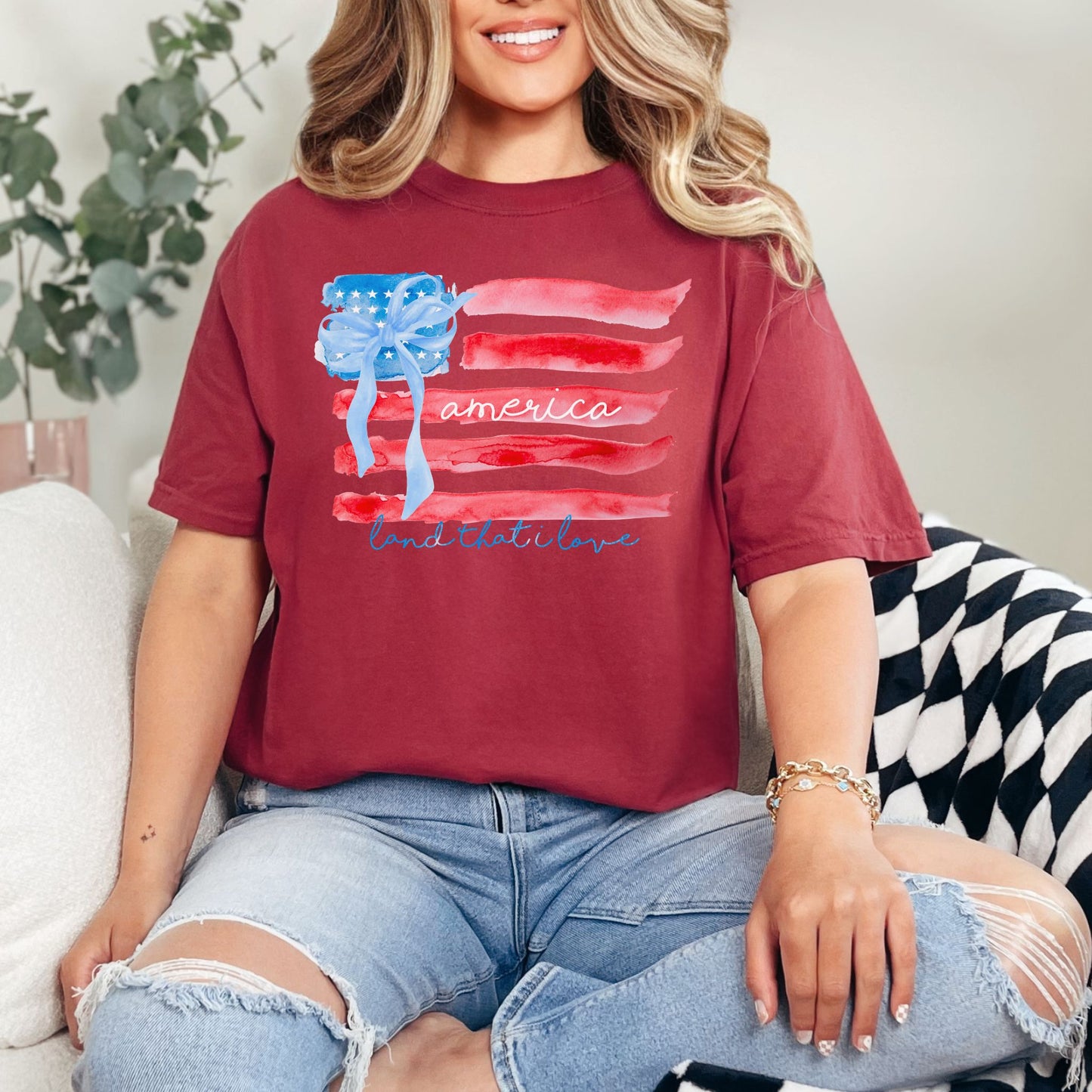 "Coquette Watercolor American Flag" graphic on muted brick red (chili) T-shirt.